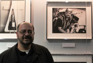 Greg Cecil poses in front of his own photo at the Space Shuttle Atlantis exhibit at the Kennedy Space Center